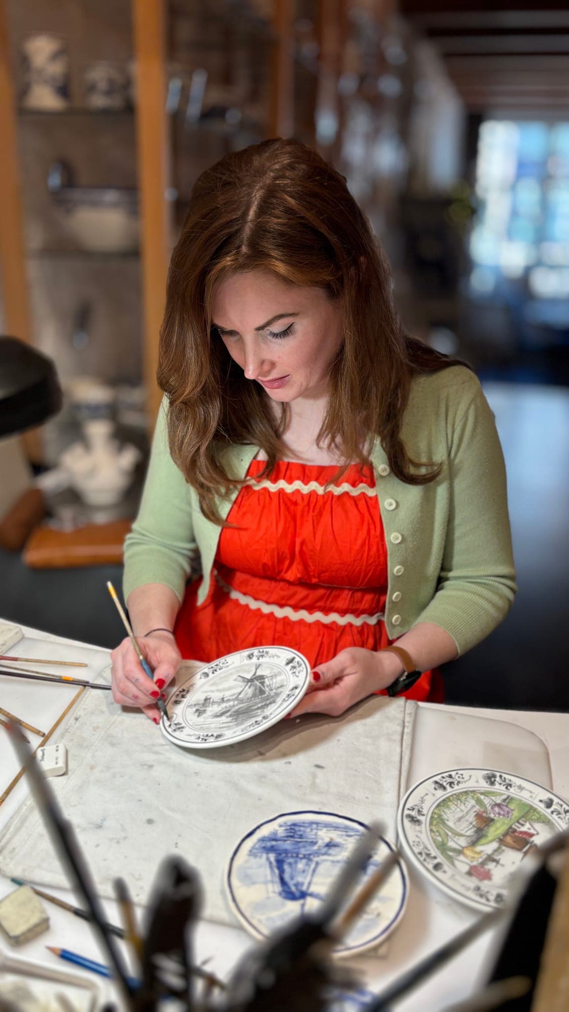 Lydia hand-painting a Delft Blue plate